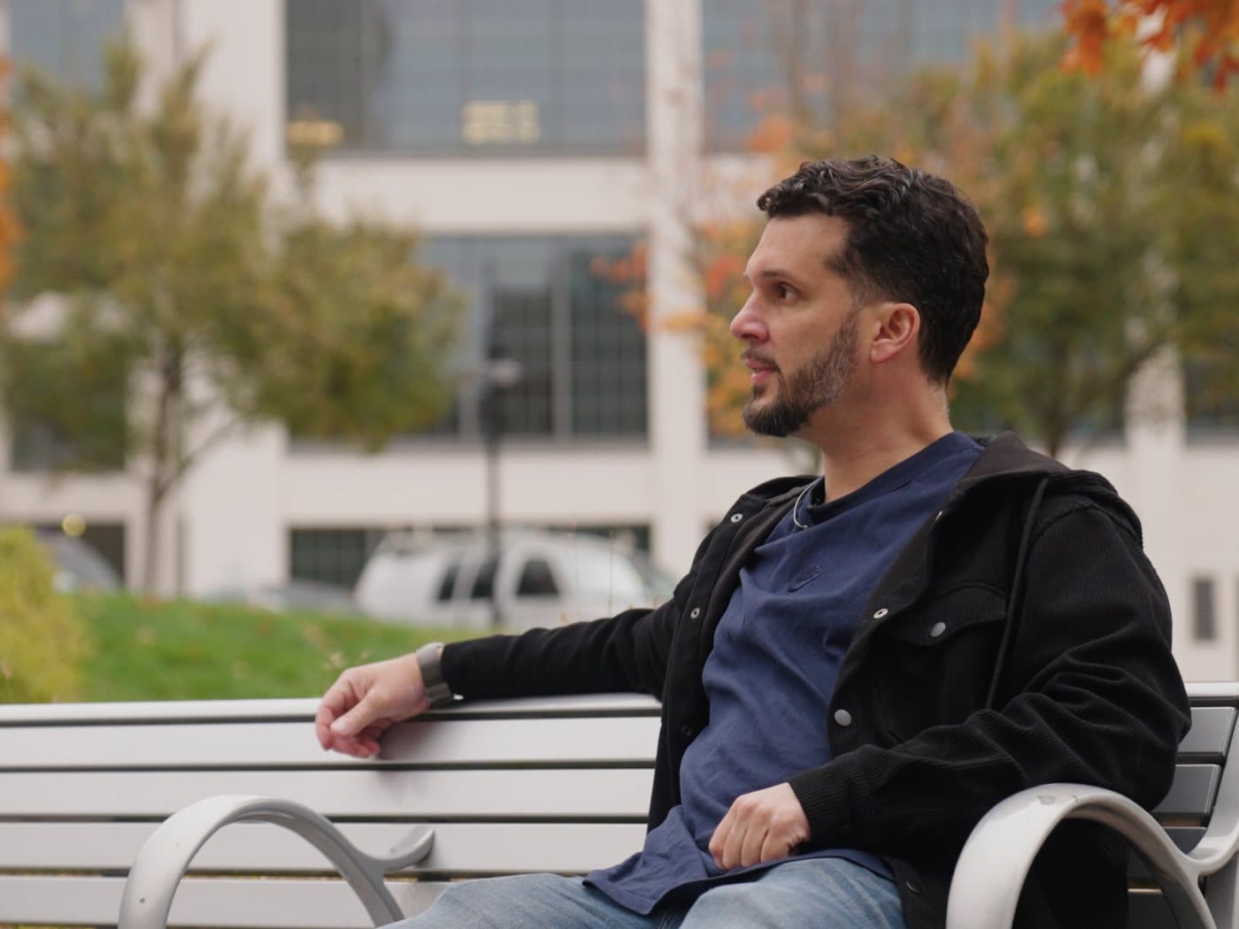 Subject filmed on location for a Lenny J Media brand film, seated on a bench outside a downtown office building
